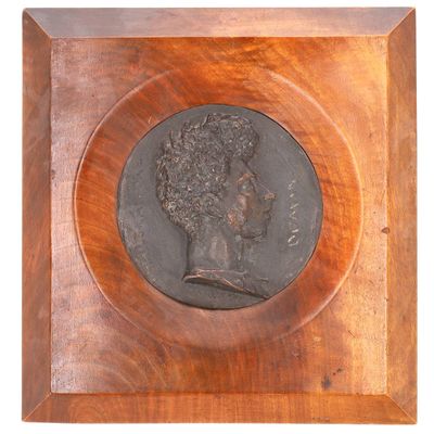 un gros plan sur une plaque en bois sur laquelle figure le buste d'un homme
