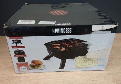 la boîte est ouverte sur une table, à côté d'un grill et d'une assiette de nourriture