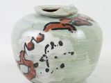 a green vase with a red and black design on it