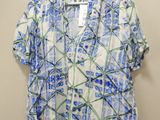 a white shirt with blue flowers on it hanging on a hanger