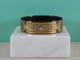 a close up of a black and gold bracelet on a marble block