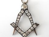 a close up of a masonic square and compass charm