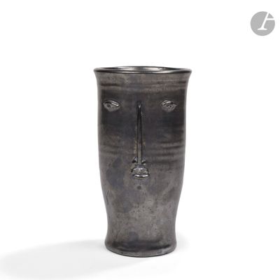 un vase noir orné d'un visage sur fond blanc