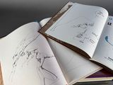 an open book with drawings on it sitting on a table
