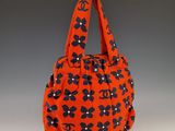 un sac à main orange orné de fleurs noires et blanches