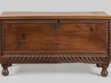 an old wooden chest with a carved top and legs