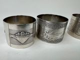 three silverplated cups with designs on them sitting on a white surface