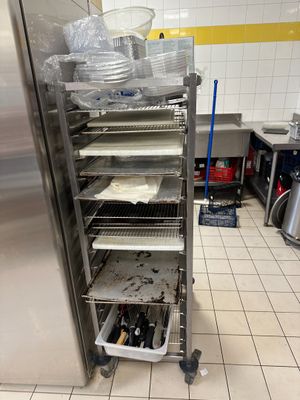 Plusieurs plateaux de nourriture sont empilés sur une étagère métallique dans une cuisine