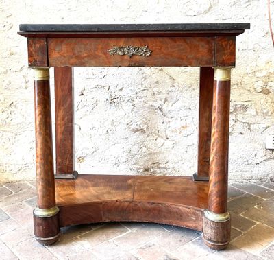 a small wooden table with a marble top on a brick floor