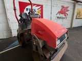 an image of a red and black road roller in a garage