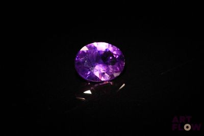 a close up of a purple stone on a black surface