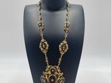 a black mannequin with a gold and black necklace on it