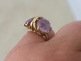 someone is holding a ring with a purple stone on it