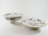 two plates with flowers on them on a white surface