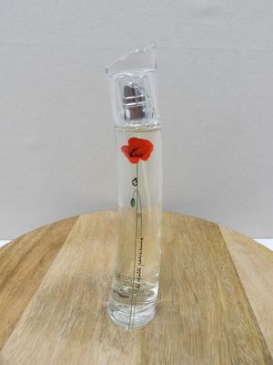 a small glass bottle with a red flower in it on a wooden table