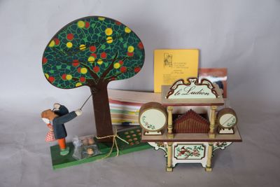 une figurine représentant un homme tenant une horloge devant un arbre