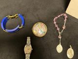 three different watches, bracelets, and necklaces are sitting on a table