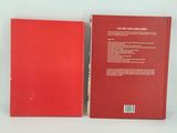 a red book sitting on top of a table next to a white wall