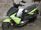 a green and black scooter parked in front of a brick wall