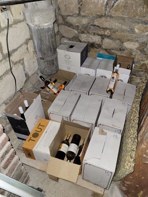 many boxes of wine sitting on the floor next to a brick wall