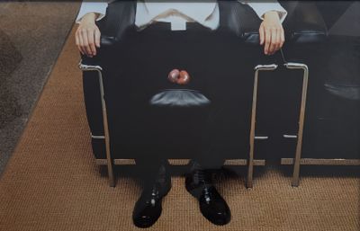 une photo d'un homme assis sur une chaise, une pomme sur les genoux