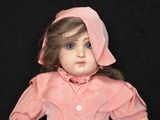 a doll that is wearing a pink dress and a pink hat
