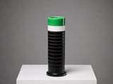 un vase noir et blanc, surmonté d'un couvercle vert, posé sur un socle blanc