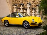 a yellow car parked in front of a stone wall