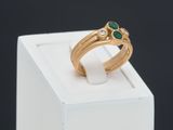 an image of a close up of a gold ring with a green stone
