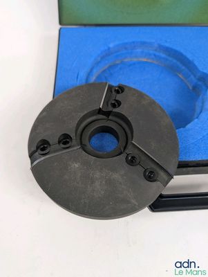 un gros plan d'un disque métallique posé sur une surface blanche, avec un fond bleu