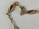 a close up of a gold necklace with a chain on a table