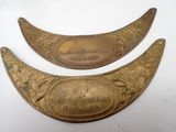 two antique brass plaques with engraved names on them on a white surface