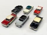 several toy cars are lined up in a row on a white surface