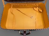 a yellow suitcase with a brown handle on a gray floor