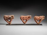 three carved figurines of birds on a stand
