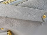 close up of the zipper of a white purse with a gold handle