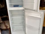 un réfrigérateur blanc dont la porte est ouverte, dans une pièce