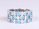 a close up of a blue and white diamond ring on a white surface