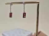 a pair of earrings that are sitting on a stand