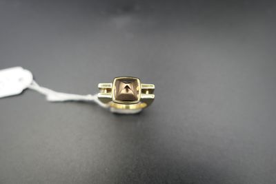 un gros plan d'une bague en or sertie d'une pierre marron