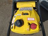 a yellow pressurer sitting on the ground next to a garage