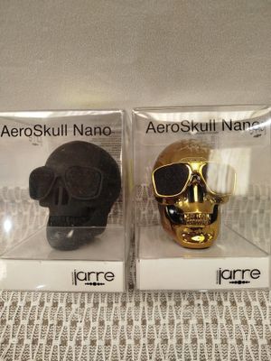 pair of black and gold skulls in clear boxes on lace tablecloth