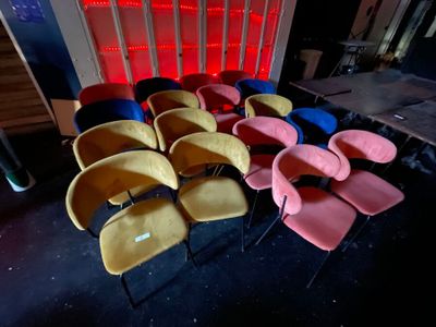 brightly colored chairs are lined up in a row in a dark room