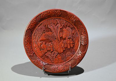 une assiette rouge décorée, posée sur un socle