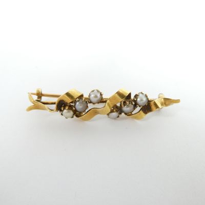 a close up of a gold and pearl hair clip on a white background