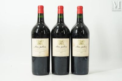 three bottles of red wine are lined up on a white surface