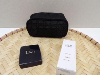 un petit sac noir posé sur une table, à côté d'un coffret de parfum