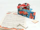 a red toy car sitting on top of a piece of paper next to a pair of scissors