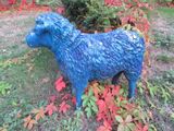 une statue bleue représentant un mouton debout dans l'herbe