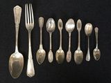 a lot of silver spoons and forks on a black table
